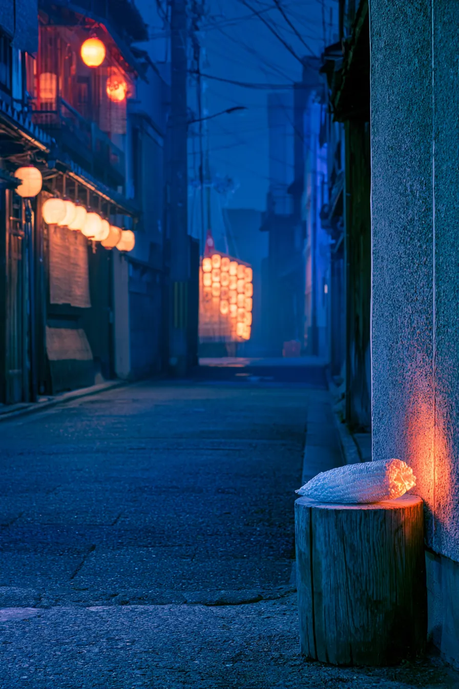 Yoiyama festival street at night: the lit lanterns of the Naginata-boko float at the end of a Kyoto lane, paper lanterns